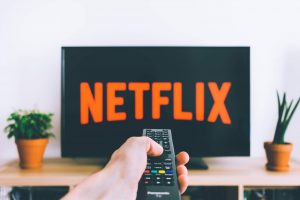 Man pressing remote control to watch Netflix